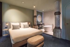 een slaapkamer met een groot bed en een bad bij Heavens Hotel in Hoorn