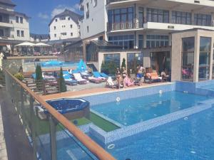a swimming pool with people sitting on lounge chairs and a building at Kopaonik Apartmani Milmari - Katic in Kopaonik