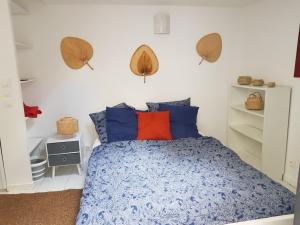 een slaapkamer met een bed met blauwe en oranje kussens bij Studio chez Thomas in Parijs