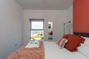 a bedroom with a bed with a blanket and a window at Sea Views Modern Two Bedroom Apartment in Lowestoft