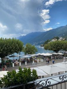 a market with tables and umbrellas and a body of water at Al Faro in Ascona