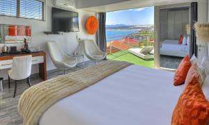 a bedroom with a bed and a kitchen and a balcony at Sea Star Lodge in Gansbaai