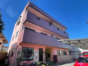um edifício cor-de-rosa com um carro estacionado em frente em near to Miyajima em Hatsukaichi