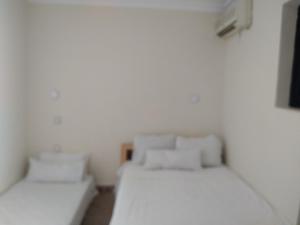 2 Betten in einem Zimmer mit weißen Wänden in der Unterkunft Riad 9 Derb El Bousnne in Marrakesch