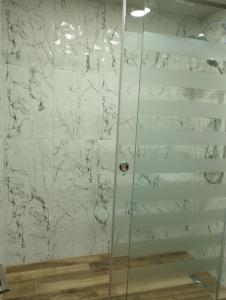 a shower with white marble walls and a glass door at Tsovella House in Jermuk