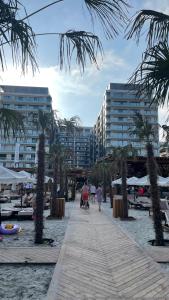 a boardwalk on a beach with palm trees and buildings at Metamorfoz Apartment in Mamaia Nord +25 photos