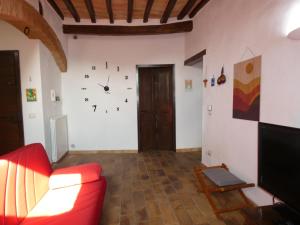 - un salon avec un canapé rouge et une horloge murale dans l'établissement SCAPPO IN UMBRIA, Porta Leone, à Amelia