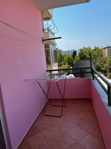 einen Glastisch auf dem Balkon einer rosa Wand in der Unterkunft Appartamento incantevole con posto auto privato in Vlorë