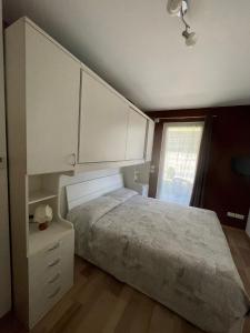 Schlafzimmer mit einem Bett mit weißen Schränken und einem Fenster in der Unterkunft ReBrì Holiday Home - appartamento Canale di Pergine in Pergine Valsugana