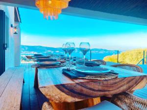 a wooden table with wine glasses and plates on it at Villa Les Alyzés in Bormes-les-Mimosas