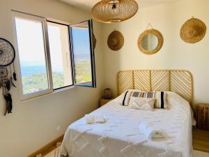 a bedroom with a bed with white sheets and windows at Villa Les Alyzés in Bormes-les-Mimosas