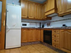 a kitchen with a white refrigerator and wooden cabinets at Los Jazmines, 2 in Granada