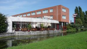 a building with tables and chairs next to a river at Atlas Hotel Holiday in Spijkenisse
