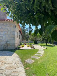 un jardín con una pasarela de piedra junto a una casa en Giesteira's House, en Arcos de Valdevez
