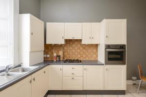 a white kitchen with white cabinets and a sink at 2 Bed Old Town Apartment - Next To Castle in Edinburgh +9 photos