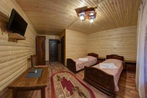 a room with two beds and a table and a tv at Villa Vlad & Spa in Bukovel
