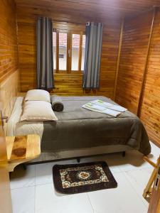 a bedroom with a bed in a room with wooden walls at Águia Dourada Hospedagem Casa 02 in Bom Jardim da Serra