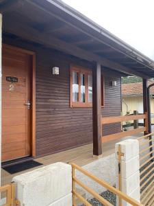 ein Holzhaus mit einer Veranda mit einer Holztür in der Unterkunft Águia Dourada Hospedagem Casa 02 in Bom Jardim da Serra