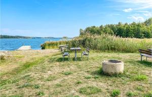 a picnic table and two chairs next to a lake at Amazing Home In Gamleby With Kitchen in Gamleby