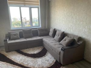 un divano in soggiorno con finestra di Appartement Kholova a Dushanbe