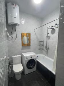e bagno con servizi igienici, vasca e lavatrice. di Appartement Kholova a Dushanbe