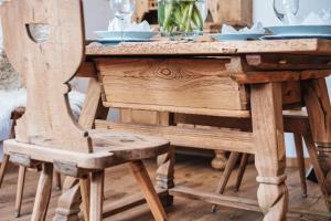drewniany stół z drewnianym krzesłem przy stole z naczyniami w obiekcie Casa Capricorn w Davos