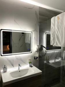 La salle de bains blanche est pourvue d'un lavabo et d'un miroir. dans l'établissement Jata Crown Hotel, à Tirana