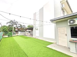 a yard with green grass in front of a house at ₘₐcₒ ₕₒₘₑ Premium Suite 3R2B CorNer @Mount Austin 【TMN DAYA】 in Johor Bahru