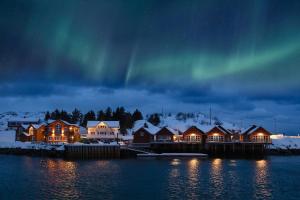 un grupo de casas con la aurora en el cielo en Reinefjorden Sjøhus en Reine