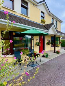 a patio with a table and an umbrella in front of a house at Killaran House in Killarney