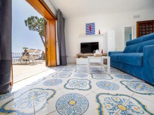 a living room with a blue couch and a tv at Villa Russo - De Vivo Realty Nerano in Nerano