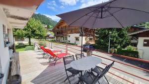 een terras met stoelen en een tafel en een parasol bij Appartement La Duchère Le Plan-la Giettaz massif des Aravis in La Giettaz