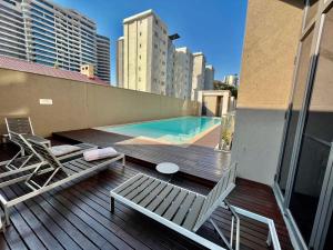 a deck with chairs and a swimming pool on a building at A cozy apartment at Sandton Skye in Johannesburg