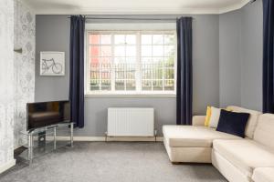 sala de estar con sofá, TV y ventana en 2 BR Royal Mile Apartment en Edimburgo