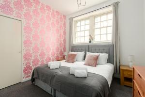1 dormitorio con 1 cama grande y papel pintado de color rosa en 2 BR Royal Mile Apartment en Edimburgo