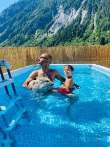 a man and a woman sitting on a surfboard in the water at Hotel La Grange - Animal Chic Hotel in Courmayeur