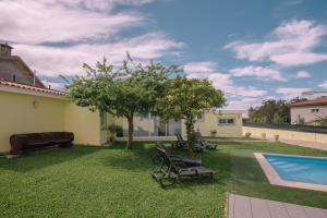 a yard with chairs and a pool and a house at Casa Dona Ermelinda - Silêncio - Conforto - Natureza in Outeiro Maior