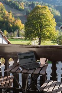 een laptop op een houten tafel op een balkon bij Hiša MIHA Stunning Spacious House & Apartment Podkoren Kranjska Gora in Kranjska Gora