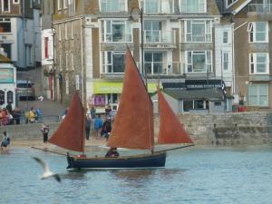 due imbarcazioni con vele rosse in un corpo idrico di The Grey Mullet Guest House a St Ives