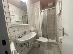 a white bathroom with a sink and a toilet at Hotel Meilchen in Dillingen an der Saar