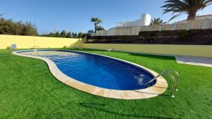 a swimming pool in the middle of a grass field at FRAMANTIS App No 6 in Costa Calma