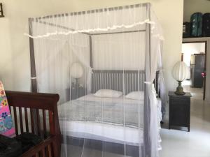 sypialnia z łóżkiem z baldachimem i białymi zasłonami w obiekcie Paradise holidays in the tropics w mieście Kottanitivu