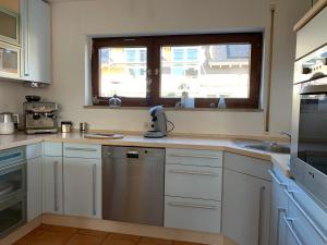 a kitchen with white cabinets and a sink and a window at Helle Wohnung mit Wintergarten, Terrasse und Garten in Bad Liebenzell