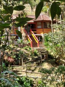a small house in a garden with a building at Monte Carmelo Inn Sana in Macaé