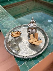 a tray with a tea pot and cookies on a table at RIAD ENNAFOURA BOUTIQUE HOTEL in Marrakech