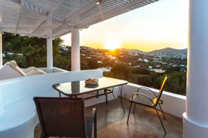 una mesa y sillas en un balcón con vistas a la puesta de sol en Hidden Oasis Private Villa, en Agia Marina