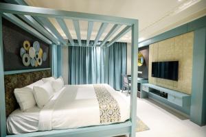 a bedroom with a bed and a television and a desk at AJ Grand Hotel in Mangalore