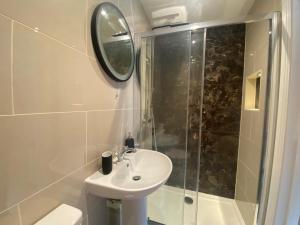 a bathroom with a sink and a shower with a mirror at Springfield Lodge - Adorable New Forest 1-bedroom guest house in Ringwood