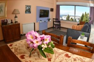 una sala de estar con una mesa con flores rosas. en Vista II Apartments en San Carlos de Bariloche