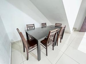 a black dining room table with wooden chairs at SingBeach holiday house in Mersing